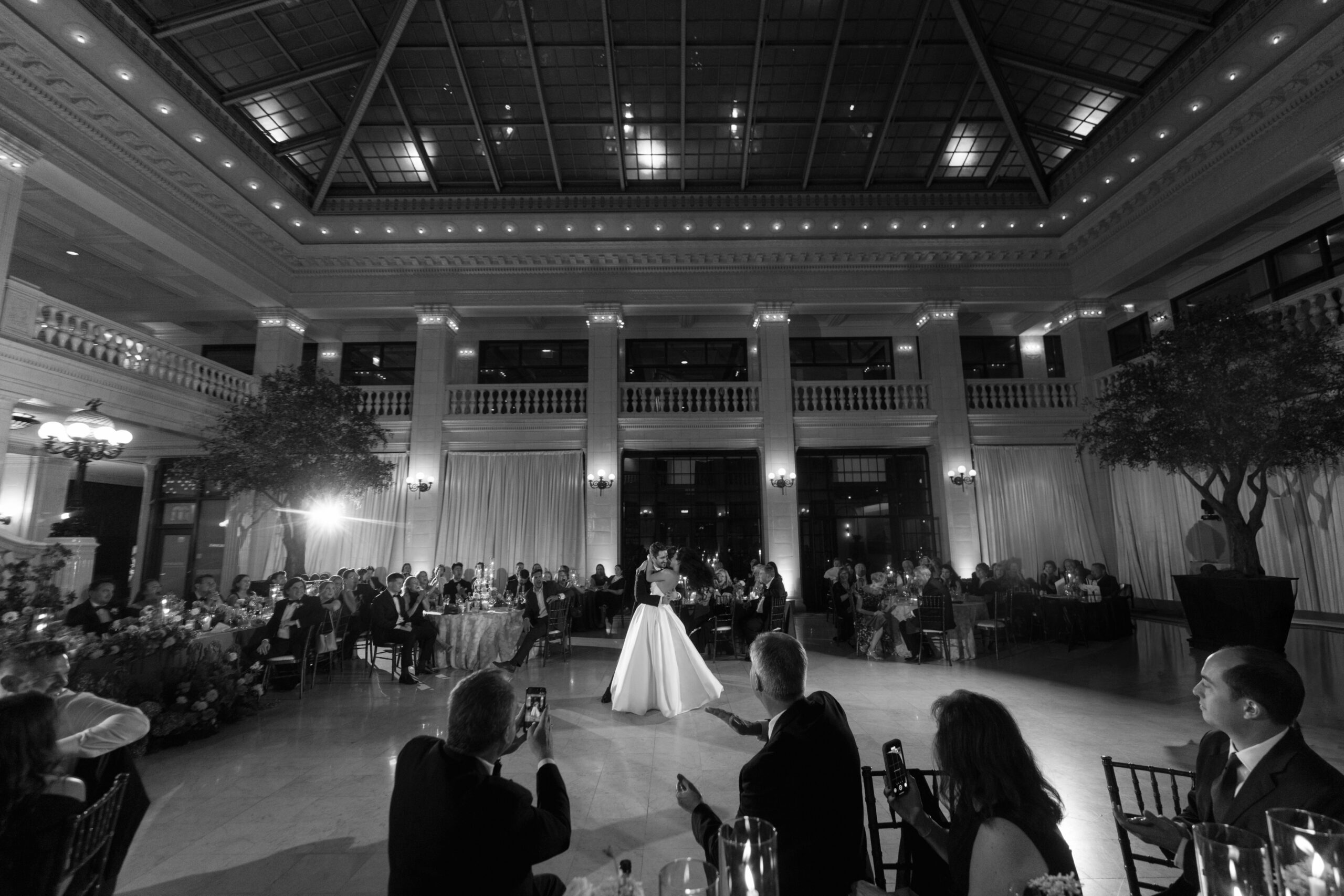 Couple sharing their first dance beneath the grand ceiling at The Exchange wedding in Chicago, surrounded by candlelit tables and guests.